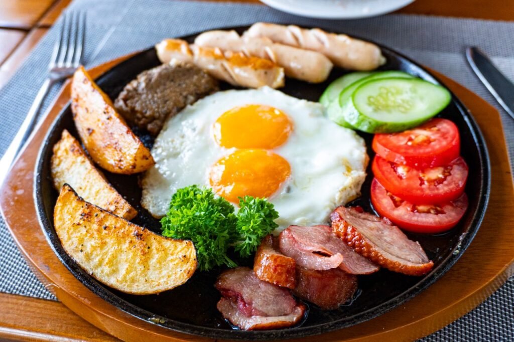 Savory full English breakfast with eggs, sausages, bacon, and vegetables.